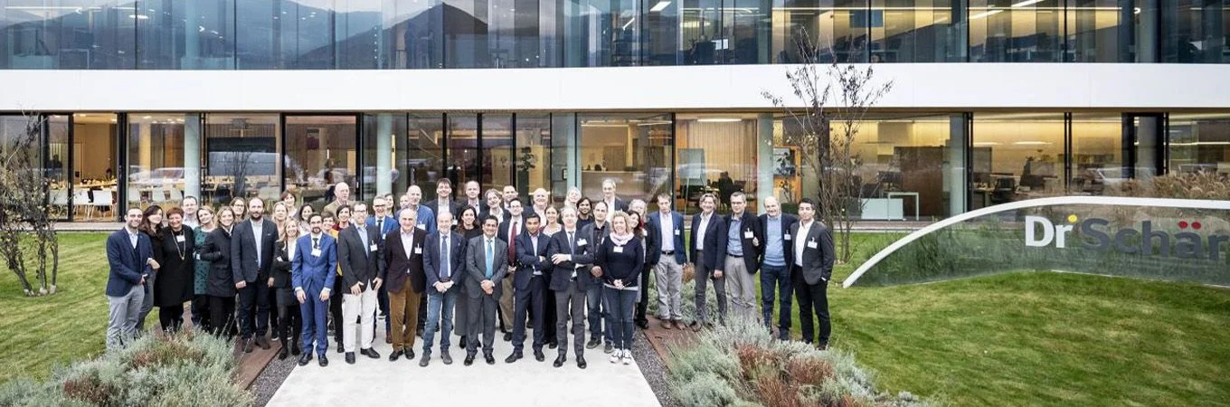 A diverse group of professionals stands in front of a modern building, showcasing teamwork and collaboration